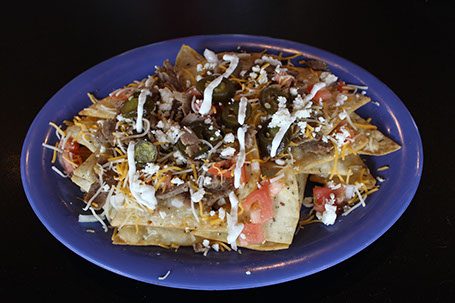 Greek nachos piled with gyro meat, feta, tomato, onion and jalapeños